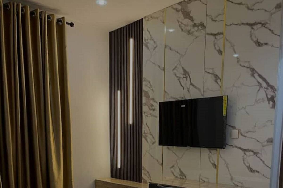 Habitació d'hotel moderna amb un llit gran, un escriptori i un televisió de pantalla plana penjada a una paret de marbre.