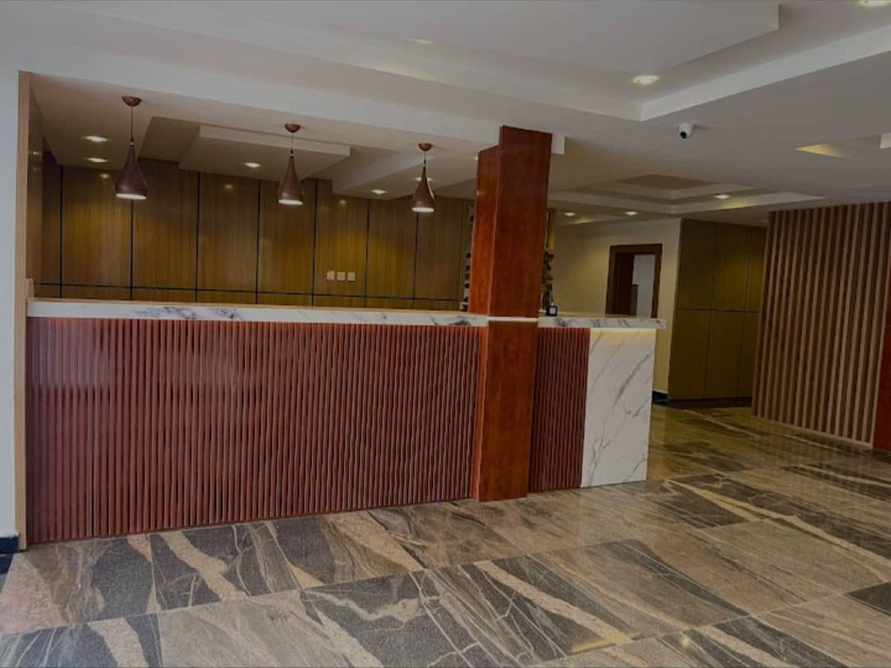 A reception area with a marble counter, wooden paneling, and pendant lighting.