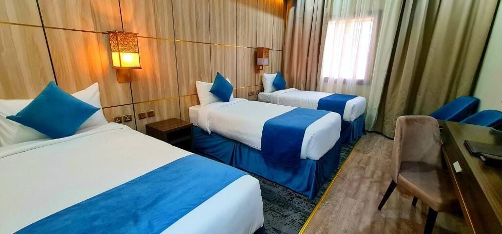 Et hotelværelse med to senge, et skrivebord, en stol og et natbord.