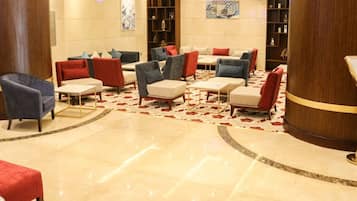 Un vestíbulo con varias zonas de estar, incluyendo sofás y sillones, dispuestos alrededor de una alfombra central.