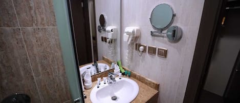 A bathroom with a sink, mirror, hairdryer, and towel rack.