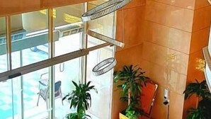 A lobby with a modern chandelier, potted plants, and a glass entrance leading to an outdoor area. - Al Ebaa Hotel (Makkah)