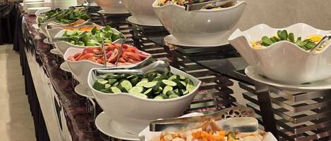 A buffet with various food items including vegetables, seafood, and salads.