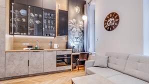 A modern kitchen with a built-in wine rack, a large decorative lion mural, and a round wall clock. - RentPlanet - Lokum Vena (Wroclaw)