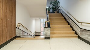 A modern staircase with marble steps and a wooden wall. - RentPlanet - Lokum Vena (Wroclaw)