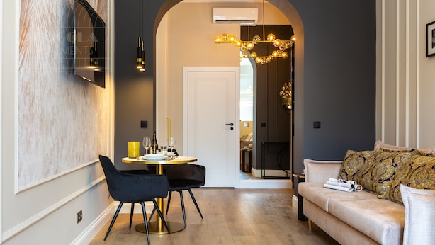 Un salon moderne avec un canapé, une table à manger et des chaises, ainsi qu’un lustre.