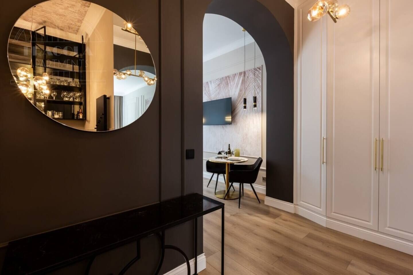 Un interior moderno con un espejo redondo, una zona de comedor con mesa y sillas, y un armario con espejo.