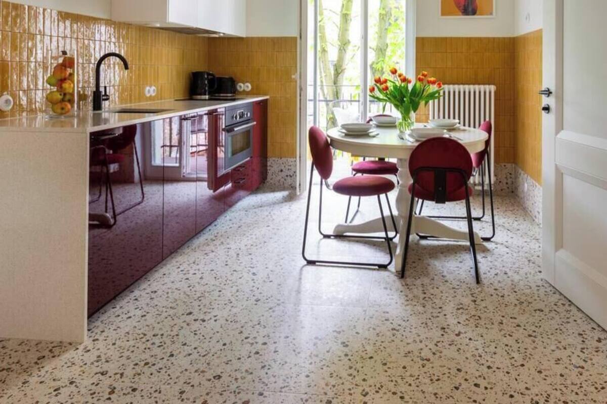 Une cuisine de taille réduite comprenant un coin repas, un radiateur et une fenêtre laissant entrer la lumière naturelle.