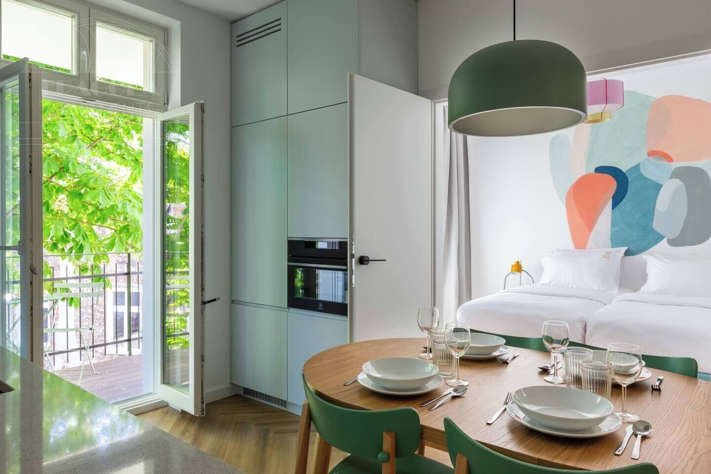 Een moderne eetruimte met een houten tafel gedekt voor vier personen, een groot raam met uitzicht op groen, en een eigentijds schilderij aan de muur.