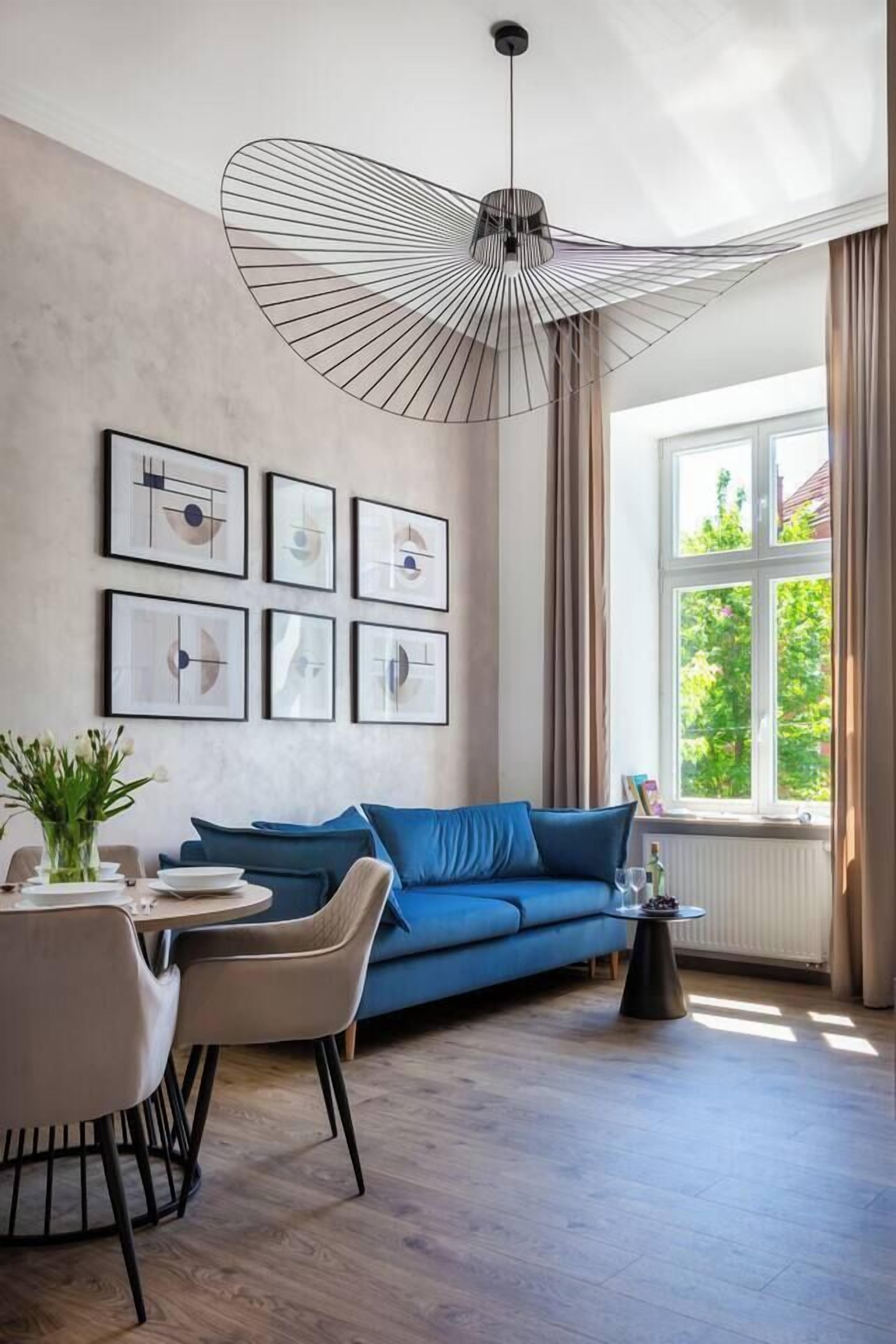 Un soggiorno moderno con un divano blu, un tavolino rotondo e un originale lampadario.