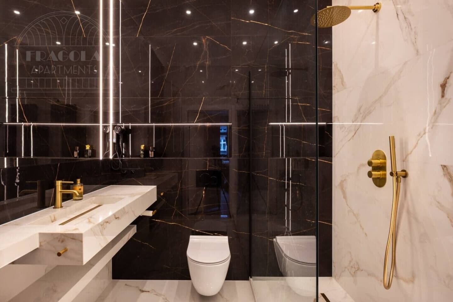 A modern bathroom with a marble vanity, a toilet, and a shower area.