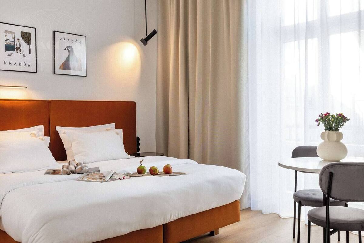 A hotel room with a bed, a table with chairs, and two framed pictures on the wall.