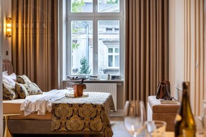 A hotel room with a bed, a small table, a window with curtains, and a bottle of wine. - Canvas House by Fragola Collection (Kraków)