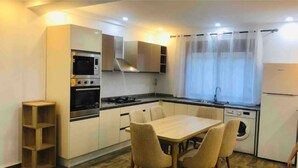 Une cuisine compacte comprenant une table à manger, un four encastré, un four à micro-ondes et un lave-linge.