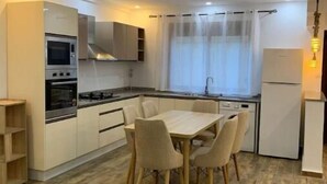 Une cuisine compacte comprenant une table et des chaises, un four encastré et un réfrigérateur.