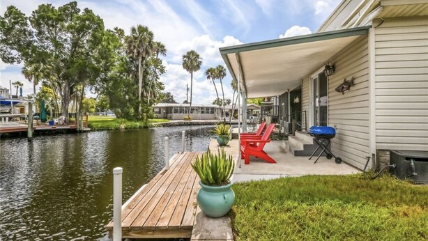 A waterfront property with a dock, outdoor seating, and a covered patio.