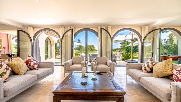 A spacious living room with a large coffee table, two sofas, and a view through arched windows. - Entre Mer, Vignes et Golf , une Maison Entièrement Refaite en 2023 (Grimaud)