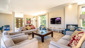 A spacious living room with a large coffee table, sofas, and a television. - Entre Mer, Vignes et Golf , une Maison Entièrement Refaite en 2023 (Grimaud)