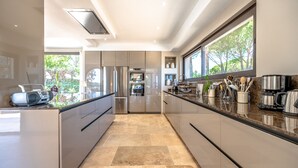 A modern kitchen with stainless steel appliances, a marble countertop, and a view of the outdoors. - Entre Mer, Vignes et Golf , une Maison Entièrement Refaite en 2023 (Grimaud)