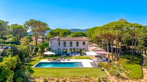 A large villa with a swimming pool, outdoor seating, and a well-maintained garden.