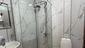 Une salle de bain avec une douche à parois de verre, un lavabo blanc et des toilettes.