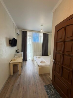 Ein Hotelzimmer mit einem Bett, einem Nachttisch, einem Fernseher und einer Tür.