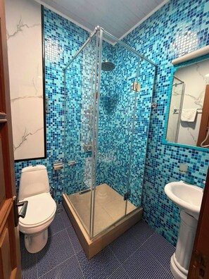 A bathroom with a glass-enclosed shower, a white toilet, and a sink with a tiled backsplash. - Hotel Old Boulevard Batumi (Batumi)