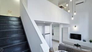 Un espacio de estar moderno con una escalera, un televisor de pantalla plana y un comedor.