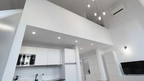 Una cocina moderna con armarios blancos, horno empotrado y televisor de pantalla plana.
