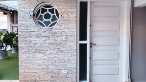 A building entrance with a stone facade, a circular window, and a white door.
