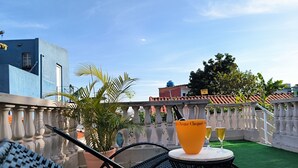 A rooftop terrace with a table and chairs, a potted plant, and a bottle of Veuve Clicquot champagne.