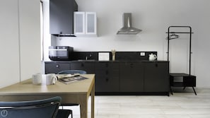 A modern kitchen with dark cabinets, a microwave, a kettle, and a coffee machine. - Italianway - Tartaglia 19 (Milan)