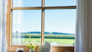 Vista dalla finestra, con un cartello che recita “Non c’è posto come casa” e un vaso con fiori bianchi su una panca di legno.