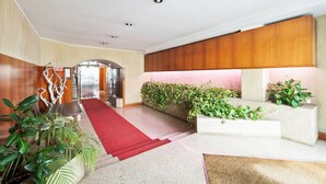 A modern lobby with a red carpet, wooden paneling, and green plants. - easyhomes - Annunciata (Milan)