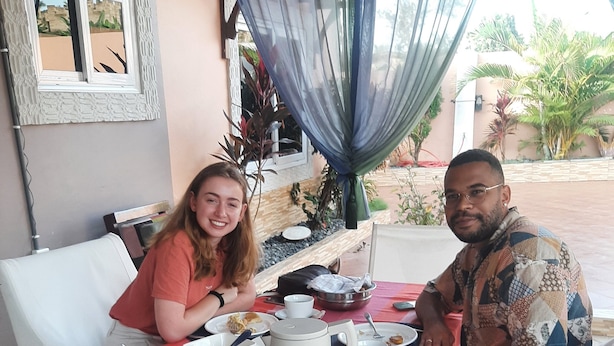 A dining table with a red tablecloth, white chairs, and various dishes and utensils. - Nana Adu's Guesthouse (Koforidua)