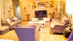 A living room with a sofa, armchairs, a coffee table, and a TV. - Nana Adu's Guesthouse (Koforidua)