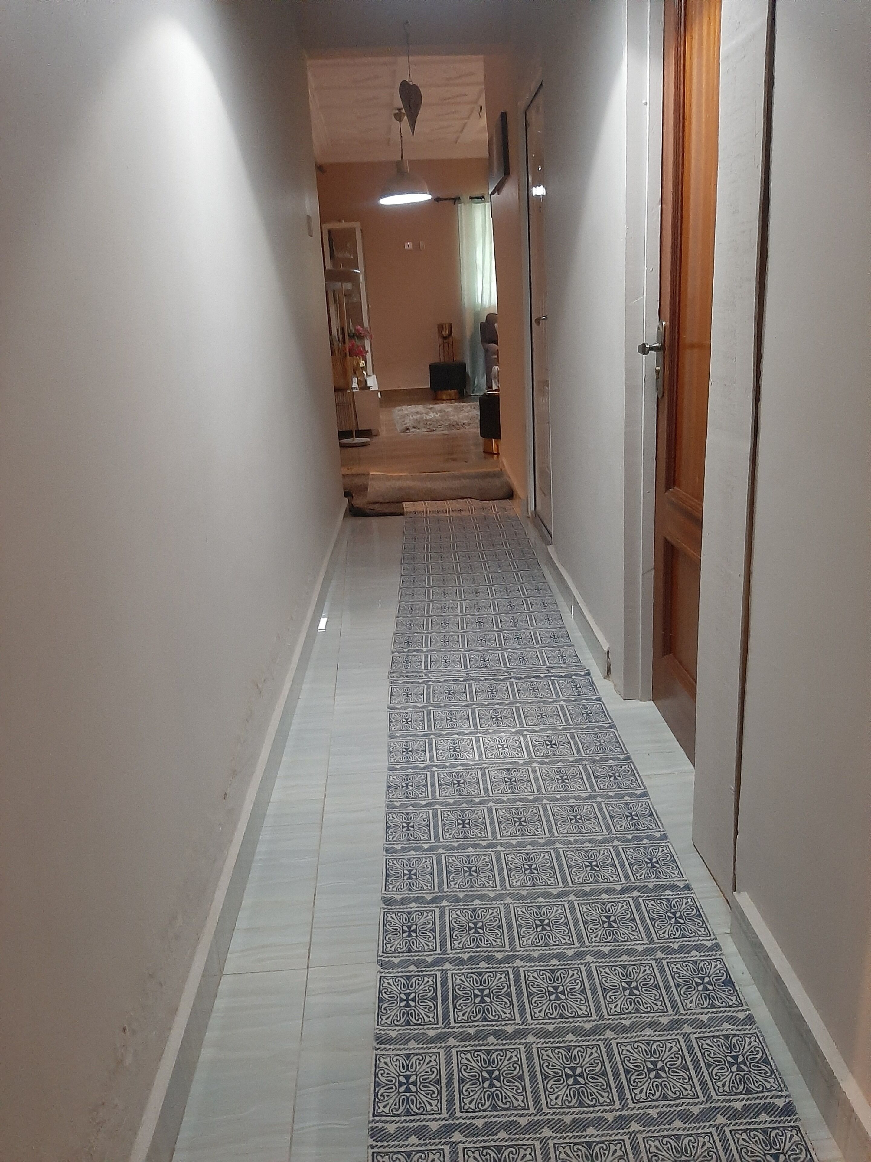 A hallway with patterned floor tiles, a ceiling fan, and a door on the right.