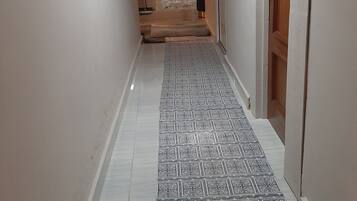 A hallway with patterned floor tiles, a ceiling fan, and a door on the right.