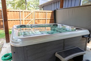 Un jacuzzi con tapa, un escalón para acceder y una manguera enrollada cerca.