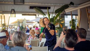 A person playing a violin in a crowded outdoor dining area with tables and chairs. - Luxery 4 persons apartment pool side (Las Lagunas de Mijas)