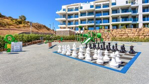 A chessboard set up outdoors with a playground in the background. - Luxery 4 persons apartment pool side (Las Lagunas de Mijas)