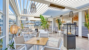 A rooftop café with tables and chairs, large windows, and hanging light fixtures. - Luxery 4 persons apartment pool side (Las Lagunas de Mijas)