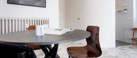A modern dining area with a round table, two chairs, a book, and a mug.