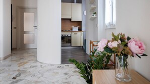 Een moderne keuken met een centraal eiland, een eethoek met een tafel en stoelen, en een bloevas op een houten tafel.