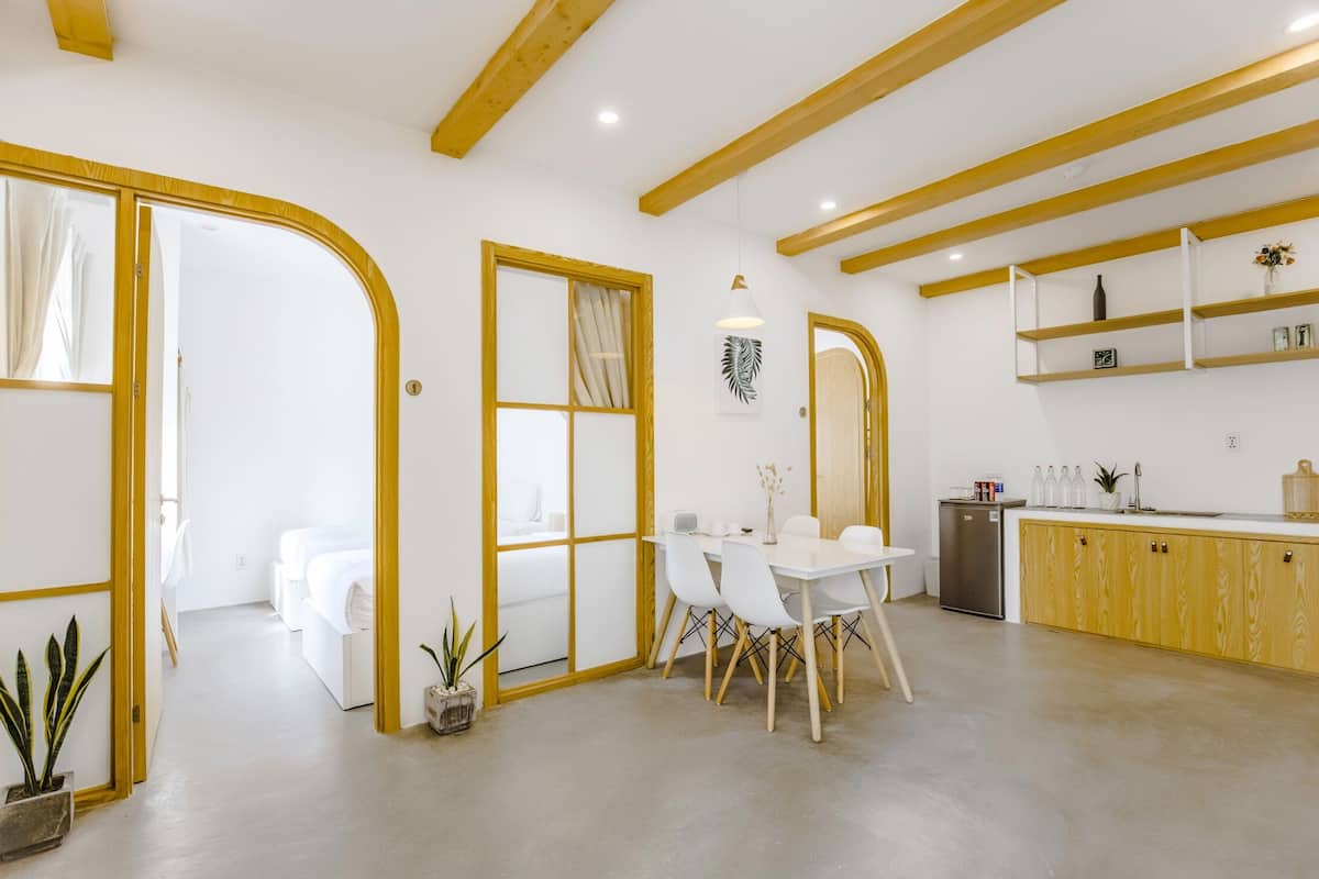 A modern kitchen with white cabinets, a wooden countertop, and a dining area with a white table and chairs.