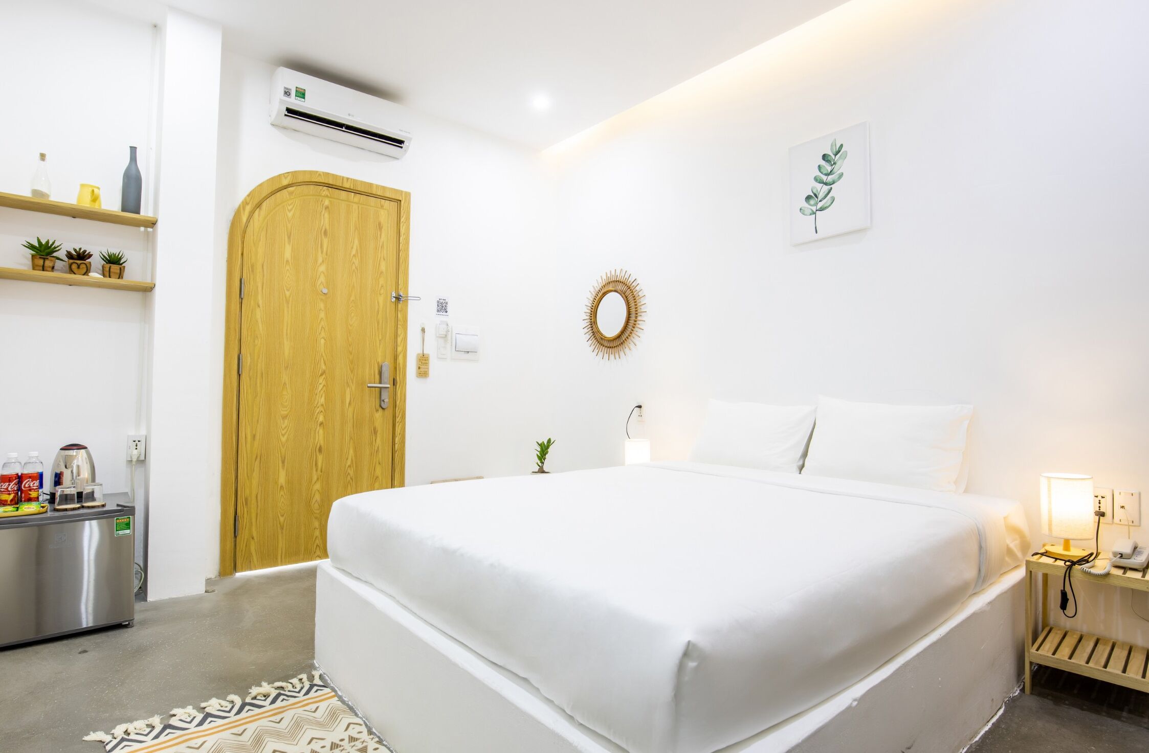 A bedroom with a bed, bedside table, lamp, and a small plant.