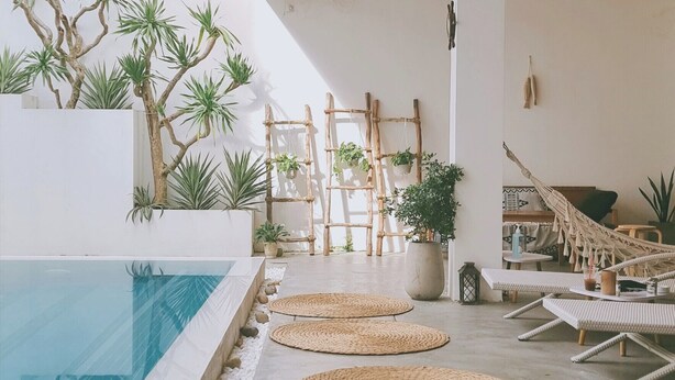 A modern indoor pool area with a wooden ceiling, lounge chairs, and potted plants. -  LaDa's House Da Nang (Da Nang)