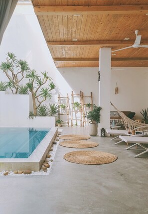 A modern indoor pool area with a wooden ceiling, lounge chairs, and potted plants. -  LaDa's House Da Nang (Da Nang)