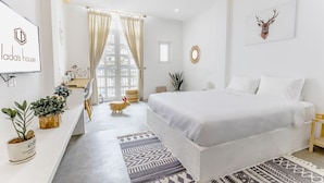 A modern bedroom with a large bed, a desk with plants, a TV, and a window with curtains. -  LaDa's House Da Nang (Da Nang)