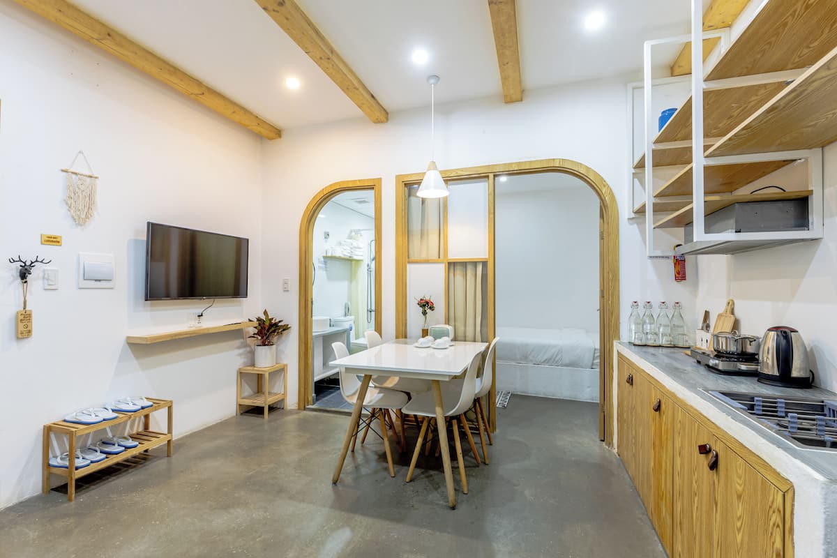 A modern kitchen with a dining area, wooden beams, a TV, and a sink.